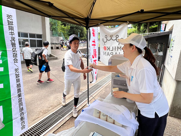 中学生野球大会で選手に牛乳を手渡す様子